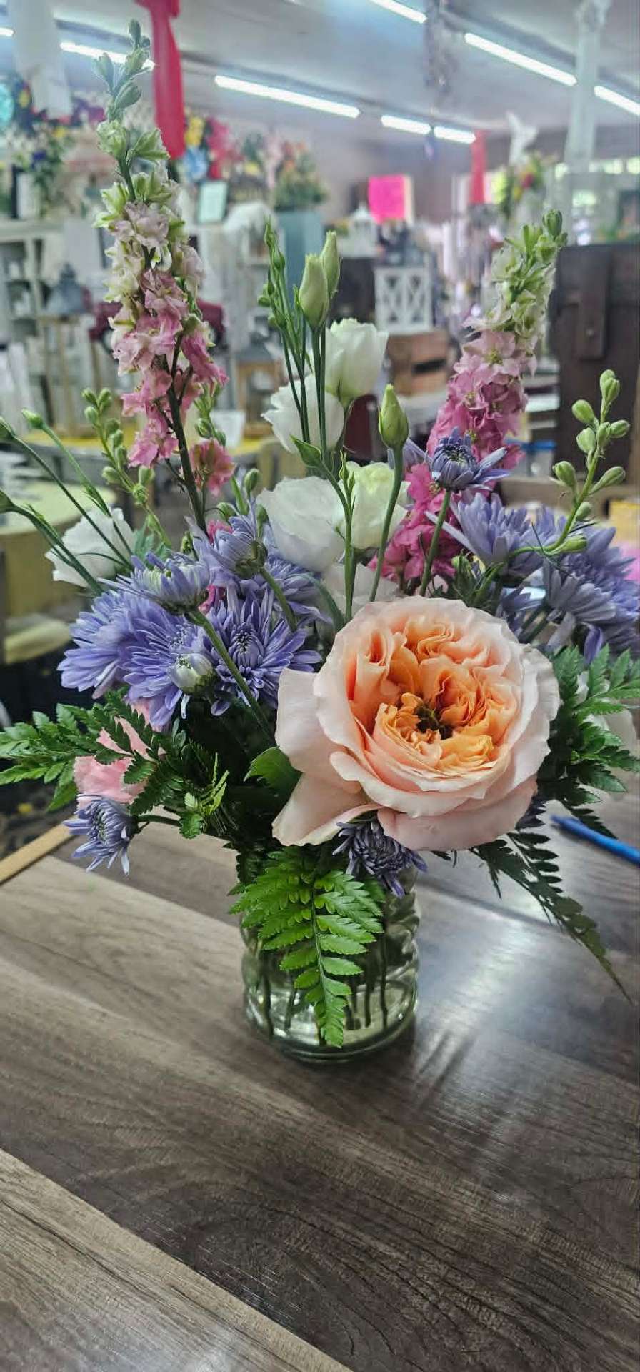 Pastel arrangement with peach garden rose, blue mums, and pink larkspur