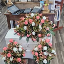 Coral and ivory rose casket spray on a rustic wooden chest