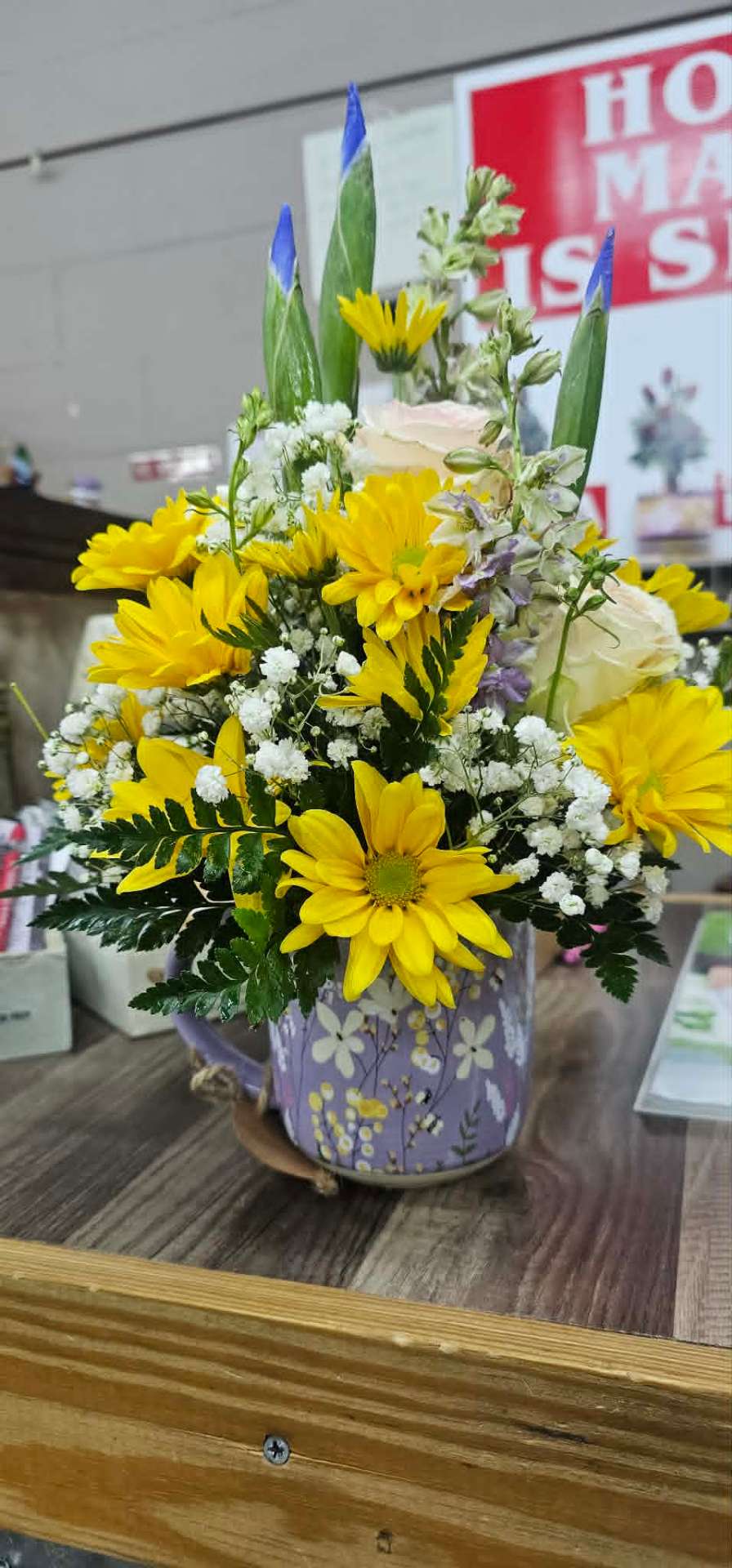Cheerful yellow daisy and iris bouquet in a lavender floral mug
