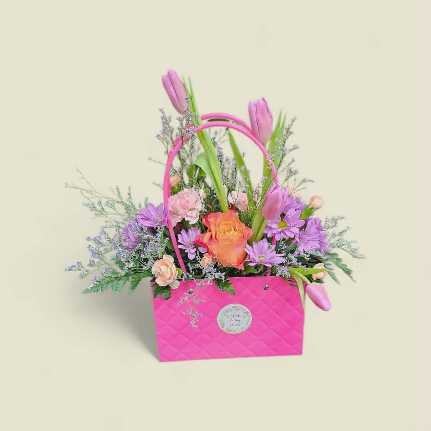 Spring tulip and rose arrangement in a pink quilted handbag