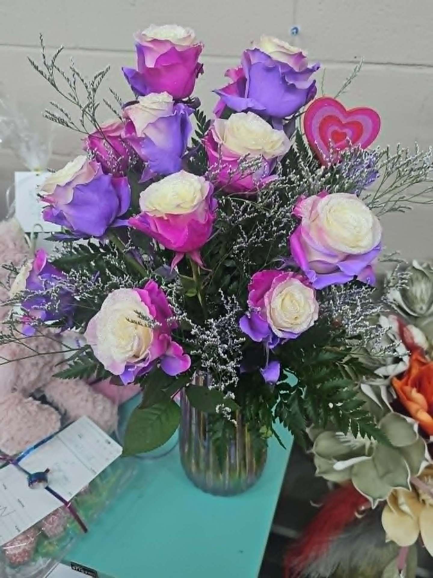 Dozen purple and ivory roses with silver caspia in a glass vase