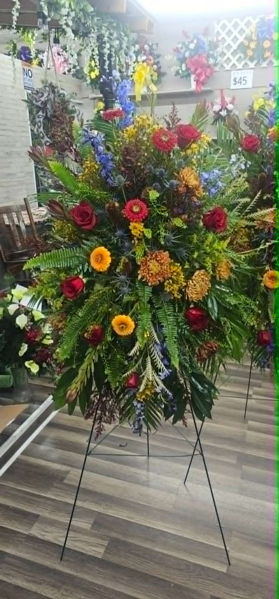 Standing memorial spray with red roses, gerberas, and ferns