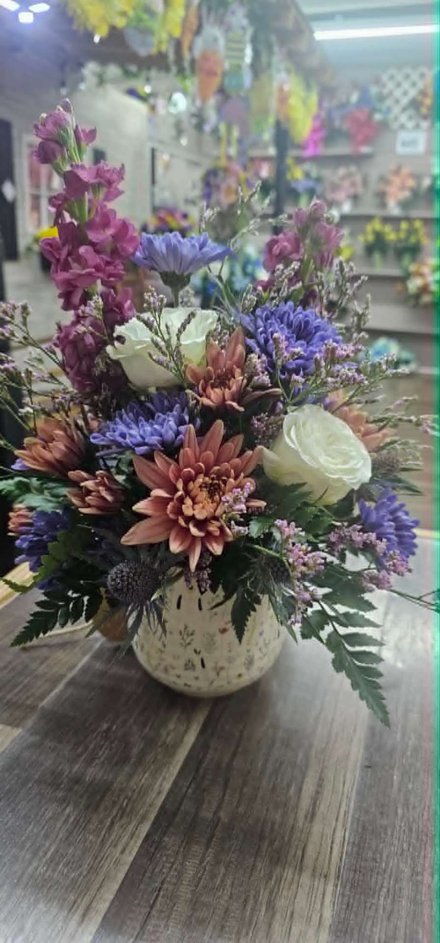 Mauve and lavender arrangement with chrysanthemums and white roses in a rustic vase