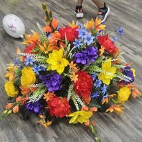 Vibrant rainbow cemetery saddle with orange, yellow, and blue blooms